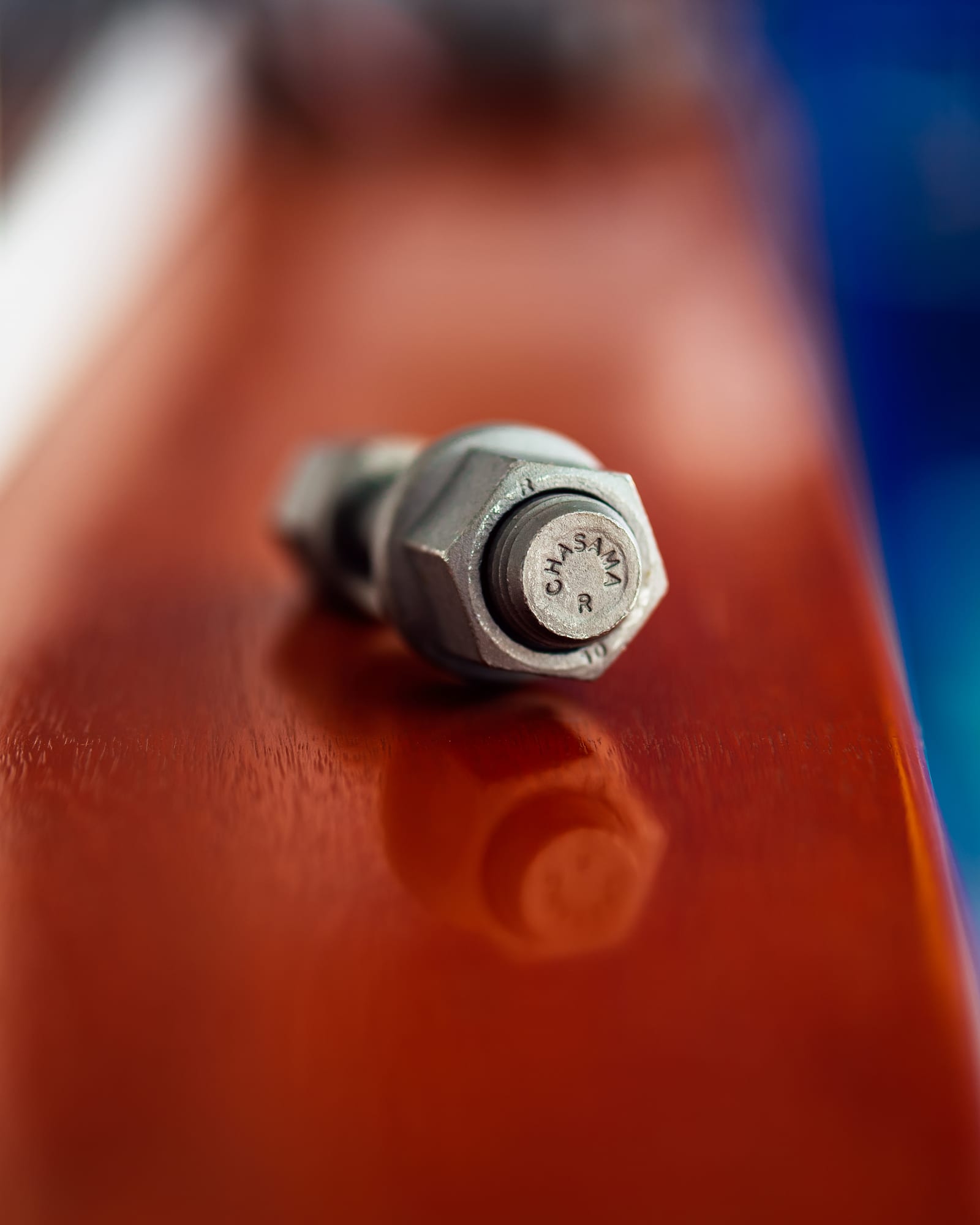 Close-up of a Chasama-stamped hex bolt and nut resting on a polished red counter
